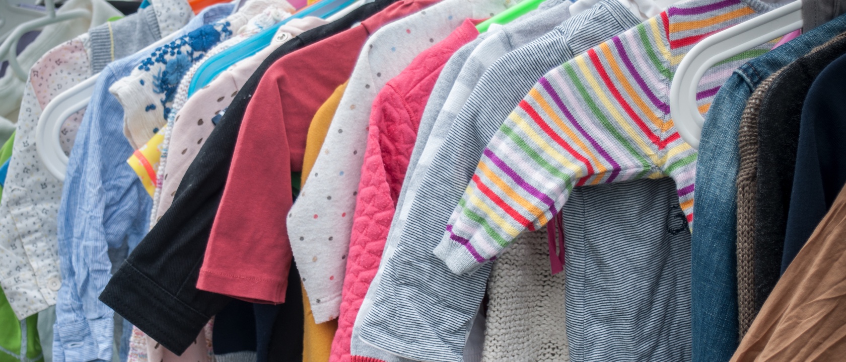 A clothes rail full of multicolored baby clothes
