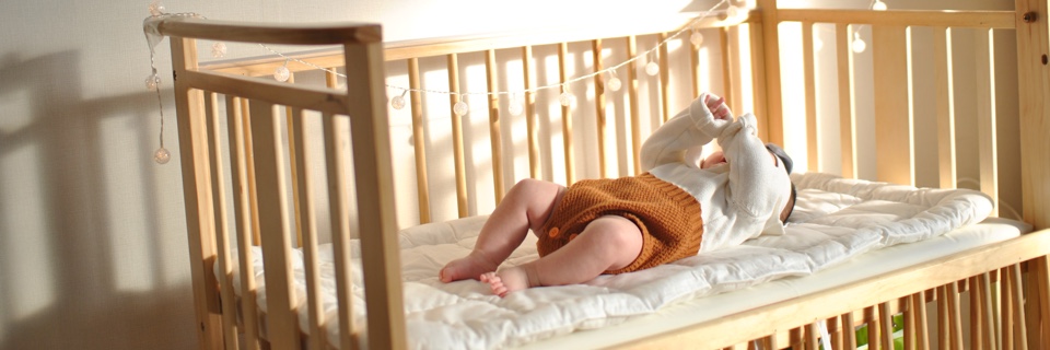 A newborn baby plays in their crib