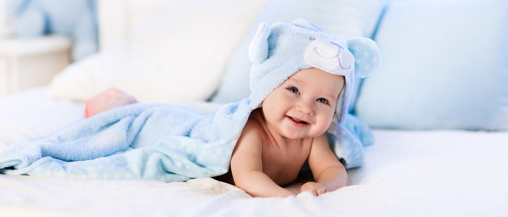 A smiling baby enjoys getting dry after a bath