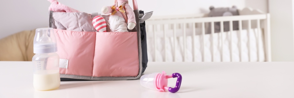 A bag packed full of baby essentials including a milk bottle, dummy and toys