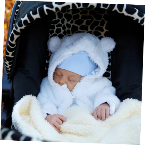 A wrapped up baby is looking content whilst taking a nap in their pram