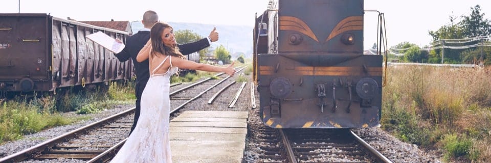 Bride and groom smiling next to a trainyard