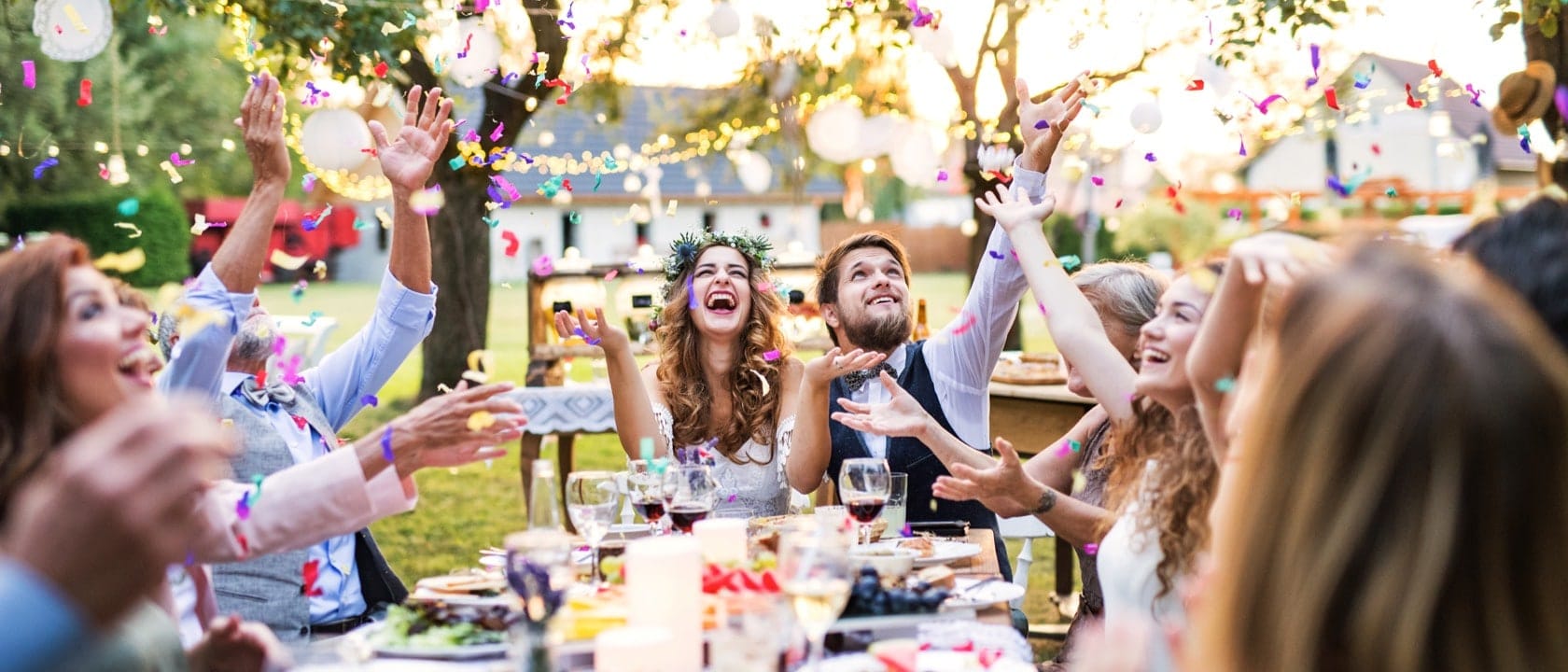Guests throwing confetti in the sky sat around a table