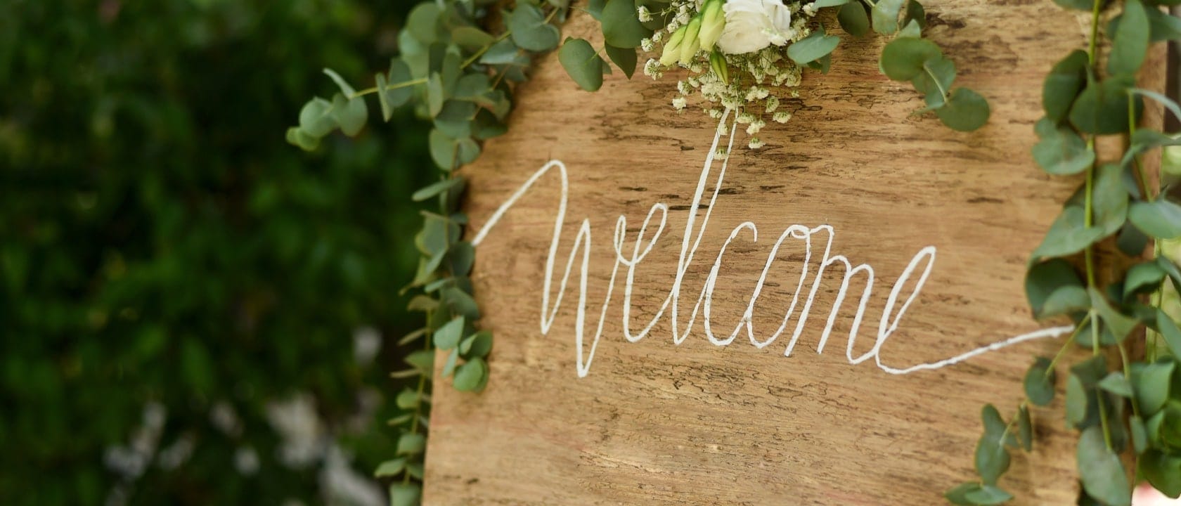 Welcome sign on a large slab of wood decorated with flowers