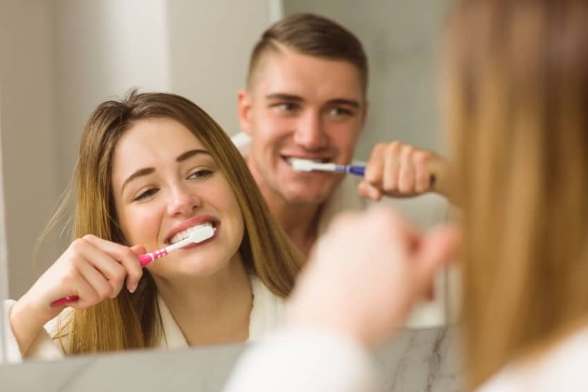 Couple brushing teeth not sharing a toothbrush