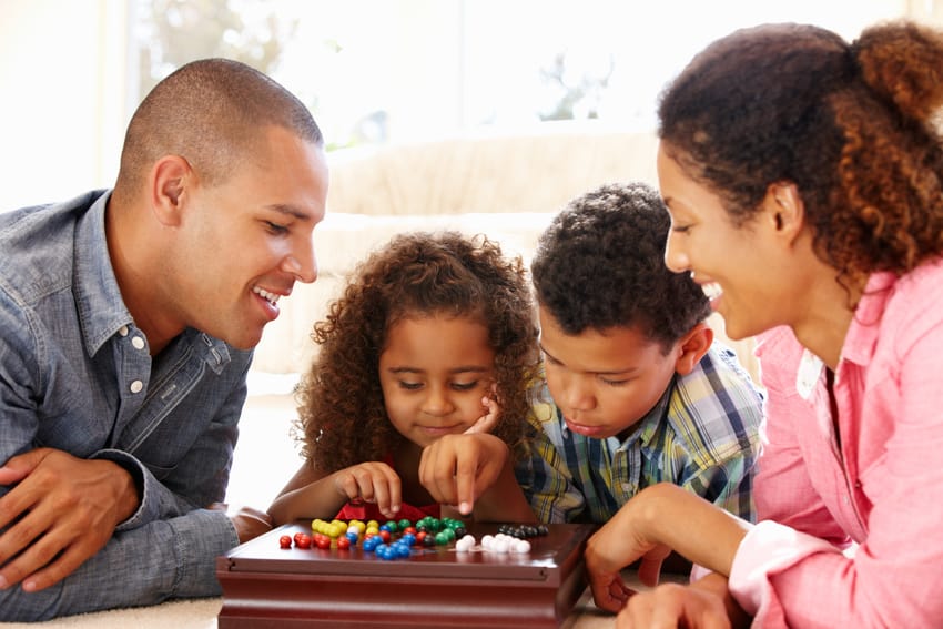 Mum Dad two children playing board game family time family games night