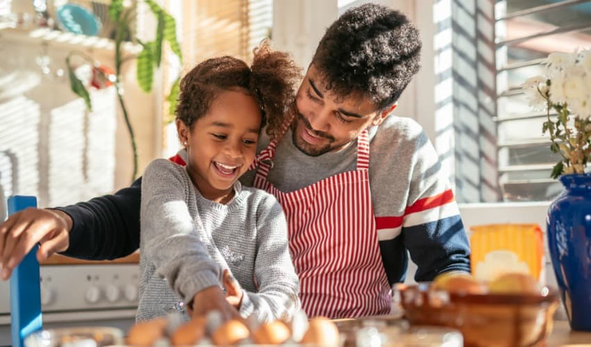 Father helping daughter to bake