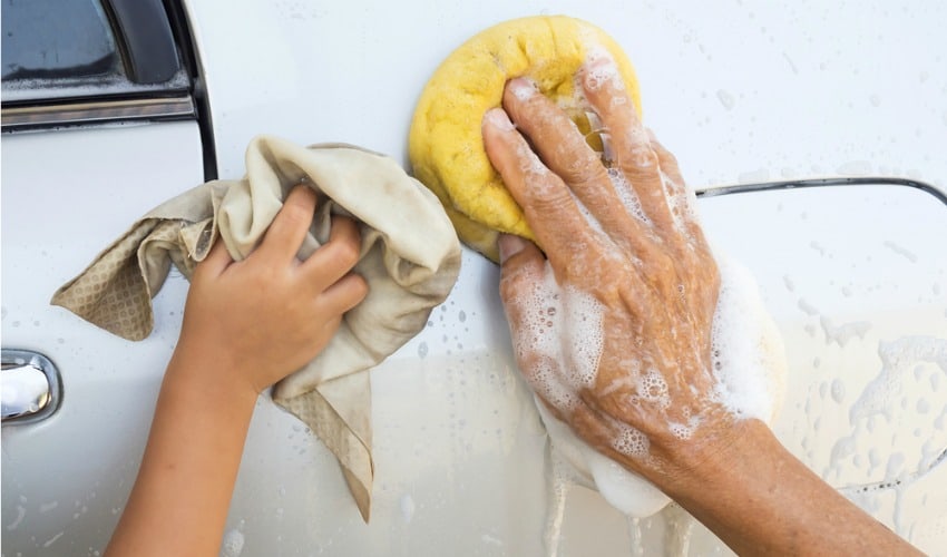 Hands of child and father washing a car