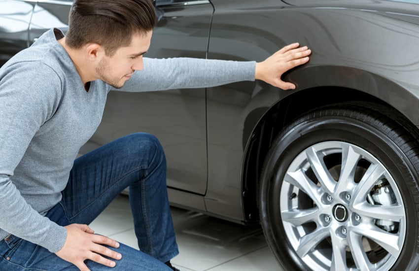 Man checking tyres on used car