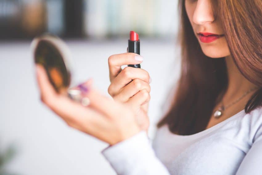 woman putting on lipstick