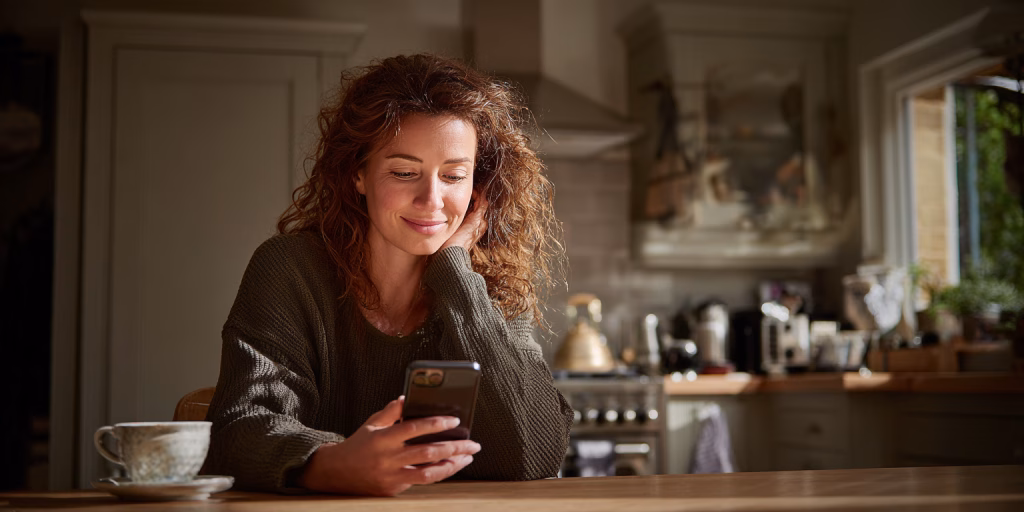 Person checking cash loan approval on mobile phone at kitchen table UK