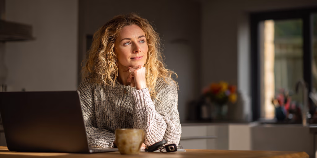 Woman reviewing £500 loan options on laptop at UK home kitchen table