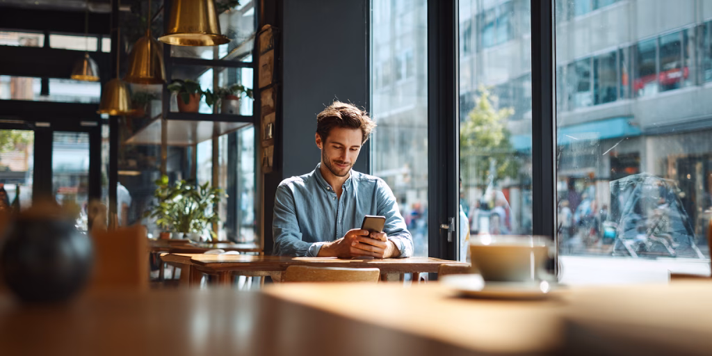 Person receiving instant £100 loan decision on mobile phone in British cafe