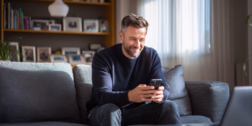 Person receiving £2000 loan approval on mobile phone in British home